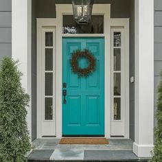 a blue front door with a green wreath on it and two lights above the door