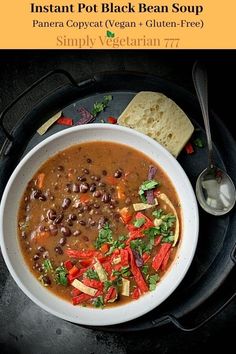 a bowl of black bean soup with tortilla chips on the side and a spoon next to it