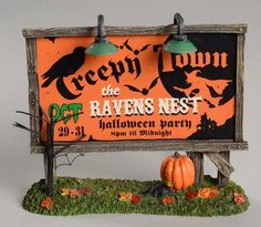 a halloween themed sign with pumpkins on the grass and lights hanging from it's sides