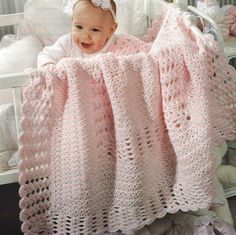 a baby in a crocheted pink blanket