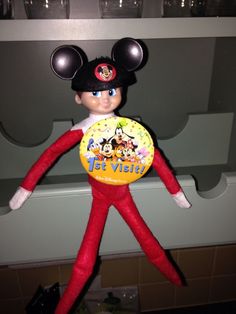 an elf with mickey mouse ears holding a frisbee in front of a shelf