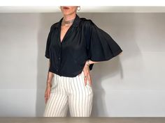 This beautiful vintage women's short-sleeve blouse features elegant pleated sleeves and a luxurious satin-like, silk-like fabric. The blouse is button-down with delicate mother-of-pearl buttons, adding a touch of sophistication. The lightweight, airy fabric makes it perfect for warm weather or layering under jackets. Measurements: Sleeve length: 27 cm (10.6 inches) Length: 66 cm (25.9 inches) Bust (underarm to underarm): 60 cm (23.6 inches) This is a unique, one-of-a-kind vintage piece that brin Satin Short, Pleated Sleeves, Retro Mode, Vintage Shorts, Blouse Vintage, Short Sleeve Blouse, Silk Satin, Warm Weather, Womens Clothing Tops