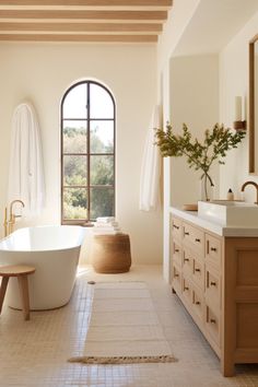 a large white bath tub sitting in a bathroom next to a sink and a window