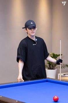 a man standing next to a blue pool table