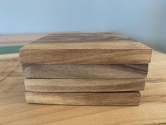 three pieces of wood are stacked on top of each other in order to be used as coasters