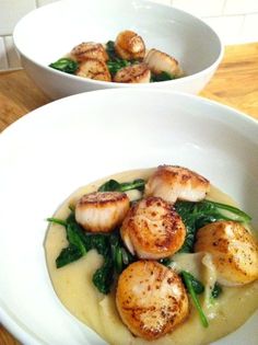 two white bowls filled with scallops on top of a wooden table next to each other