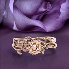 a close up of a ring on a purple surface with a rose in the background