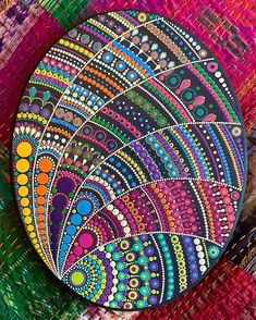 an artistically painted plate sitting on top of a colorful cloth