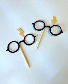 two black and gold harry potter glasses on top of each other with toothpicks in the shape of lightning bolt