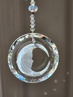 a glass ornament with a man's face in the center and three crystal beads hanging from it