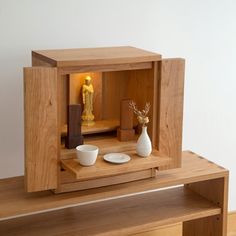 a small wooden cabinet with two bowls and a vase on the table next to it