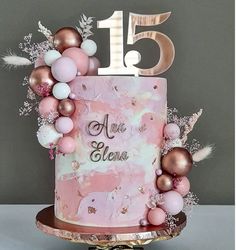 a pink and gold birthday cake decorated with balloons