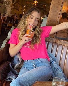 a woman sitting at a table with a drink in her hand