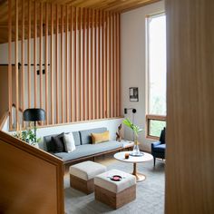 a living room filled with furniture and wooden slats on the wall next to a window