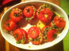 some tomatoes are in a white bowl on a table