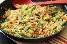 a pan filled with rice and vegetables on top of a table