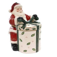 a santa clause figurine sitting on top of a canister with holly decorations