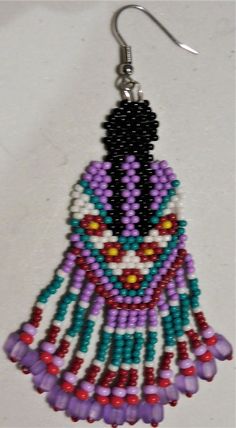 a pair of beaded earrings with beads on them, hanging from hooks in front of a white background