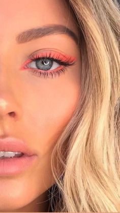 a woman with long blonde hair and bright red eye makeup looks at the camera while posing for a photo