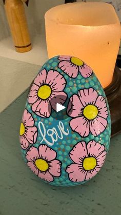 a painted rock sitting next to a lit candle on a table with the word joy written in it