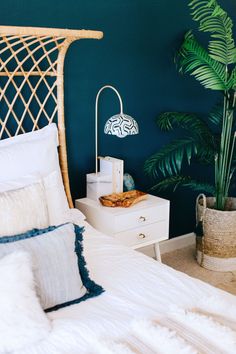 a bedroom with green walls and white bedding has a rattan headboard on the nightstand