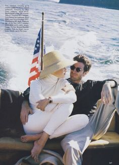 a man and woman sitting on the back of a boat with an american flag behind them