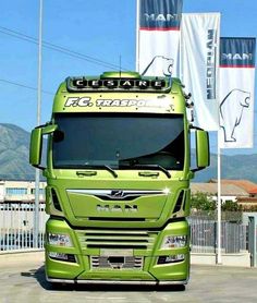 a green truck is parked in front of some flags