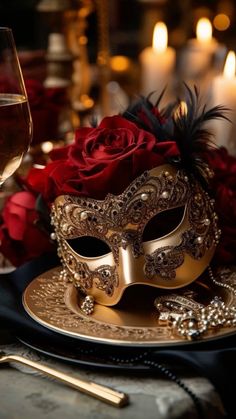 a gold plate topped with a masquerade next to a glass of red wine