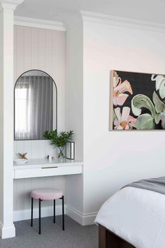 a bedroom with a bed, desk and mirror in it's corner area next to a painting on the wall