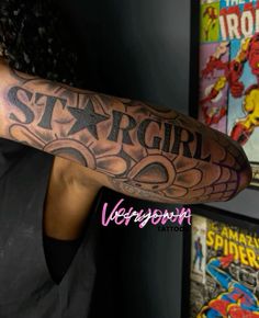 a man with a tattoo on his arm that says stargirl and is next to some comics