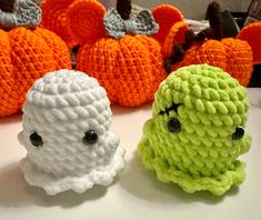 two crocheted pumpkins sitting next to each other on top of a table