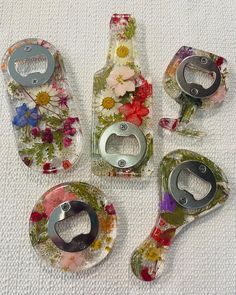 four bottle openers with flowers on them sitting next to each other in front of a white towel