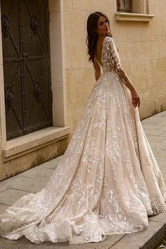 a woman in a wedding dress is standing on the sidewalk near a building and looking off into the distance