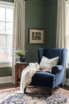 a blue chair sitting in front of a window next to a table with a potted plant on it