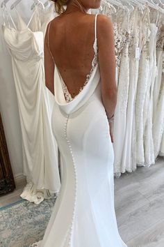 the back of a woman's wedding dress in front of a rack of dresses