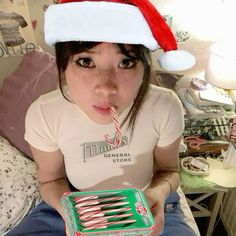 a woman in a santa hat is holding a box with candy canes on it