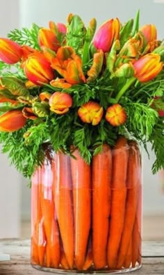 carrots and flowers in a glass vase on a table