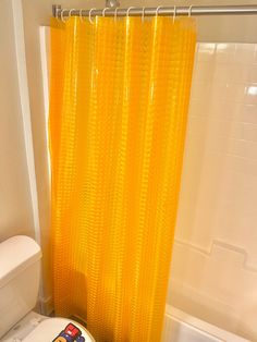 a bathroom with a yellow shower curtain next to a toilet