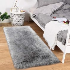 a bedroom with a bed, chair and rug on the floor in front of it