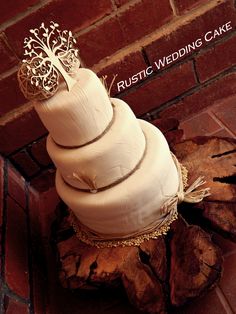 a white wedding cake sitting on top of a piece of wood next to a brick wall