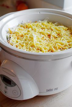 a white crock pot filled with shredded cheese