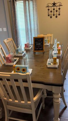 a dining room table with white chairs and a chalkboard