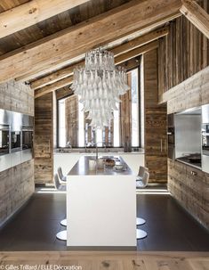 an open kitchen and dining area in a wooden house with white counter tops, wood paneling on the walls and ceiling