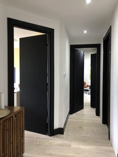 an empty hallway with black doors and white walls