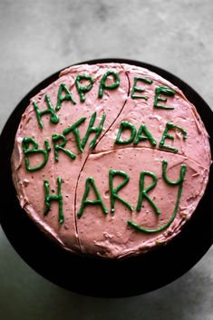 a pink cake with green writing on it that says happy birthday, bridle harry