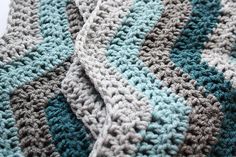 there is a blanket that has been crocheted with blue and gray stripes on it