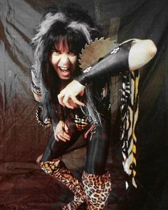 a woman with black hair and leopard print tights pointing at the camera while standing in front of a backdrop