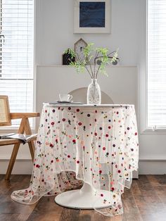 a vase with flowers on top of a table next to a chair in a room