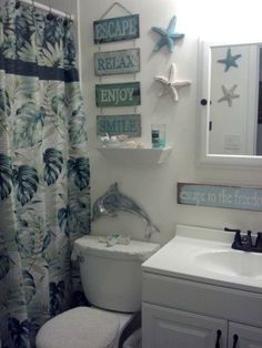 a white toilet sitting next to a bathroom sink under a mirror and a shower curtain