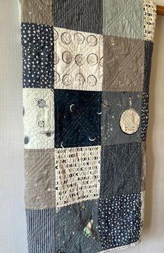 a quilt hanging on the wall next to a wooden framed frame with buttons and circles